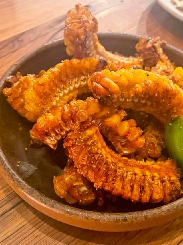 Curled corn ribs with chili butter and lime wedges