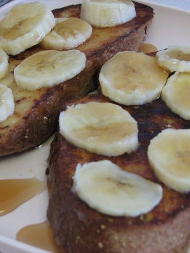 Air fryer French toast sticks stacked with a side of maple syrup