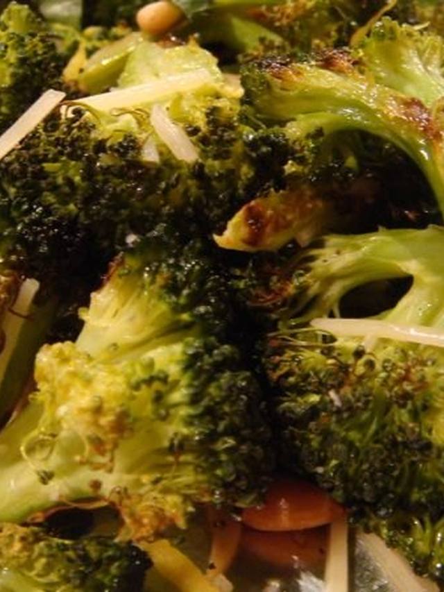 Charred broccoli florets dusted with Parmesan on a white platter