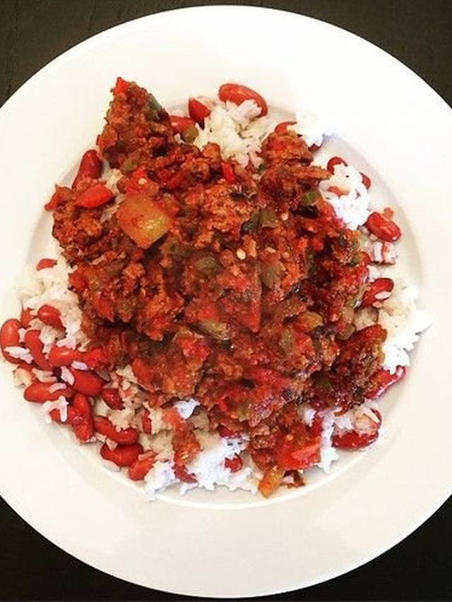 Skillet of beef picadillo with olives tomatoes and rice on the side