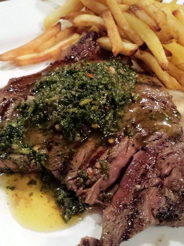 Sliced grilled flank steak topped with green chimichurri