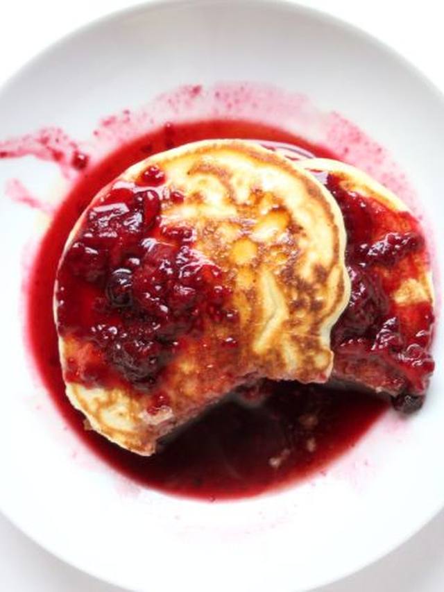 stack of golden lemon ricotta pancakes topped with warm blueberry sauce