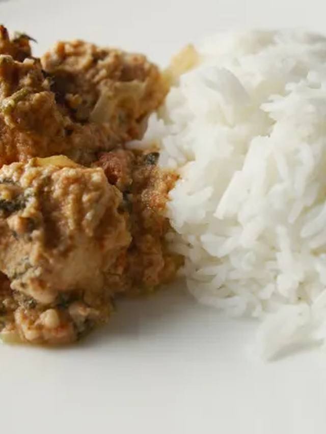 Butter chicken and rice in a pot with a swirl of yogurt