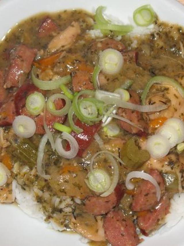 A bowl of chicken and sausage gumbo over rice with scallions