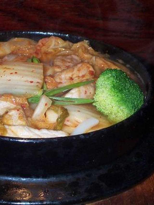 A bowl of kimchi udon with a soft egg and scallions