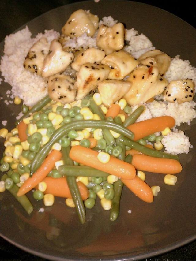 Glazed orange sesame chicken pieces sprinkled with sesame seeds in a skillet