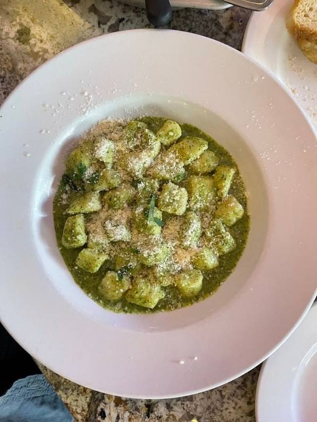 Skillet of seared gnocchi coated in pesto with bright green peas