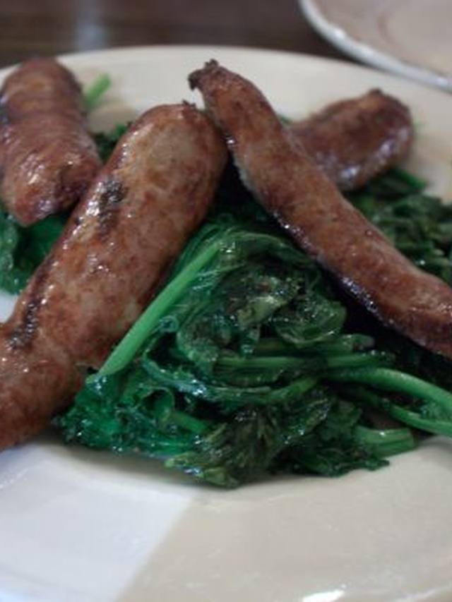 Sliced sausage and charred broccoli in a skillet