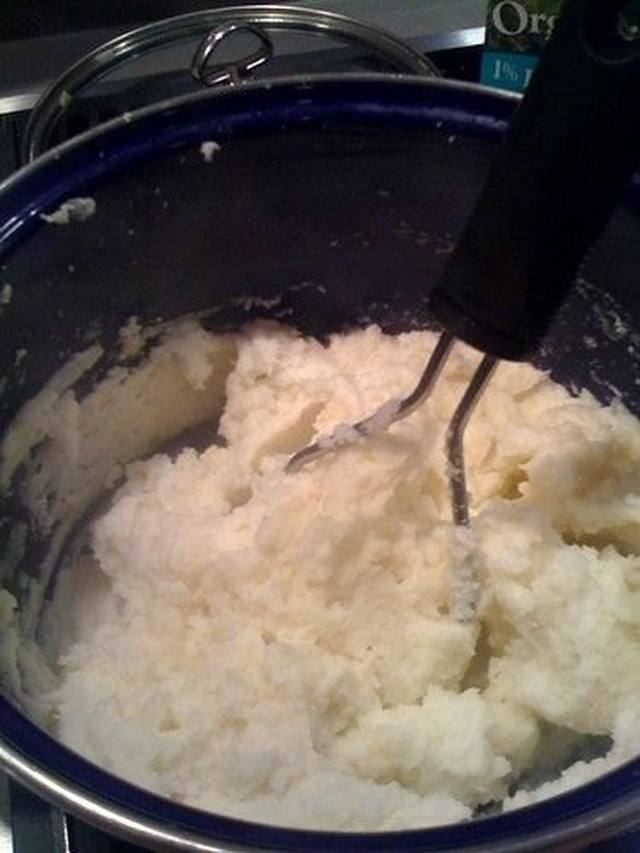Bowl of fluffy mashed potatoes with chives and a pool of butter