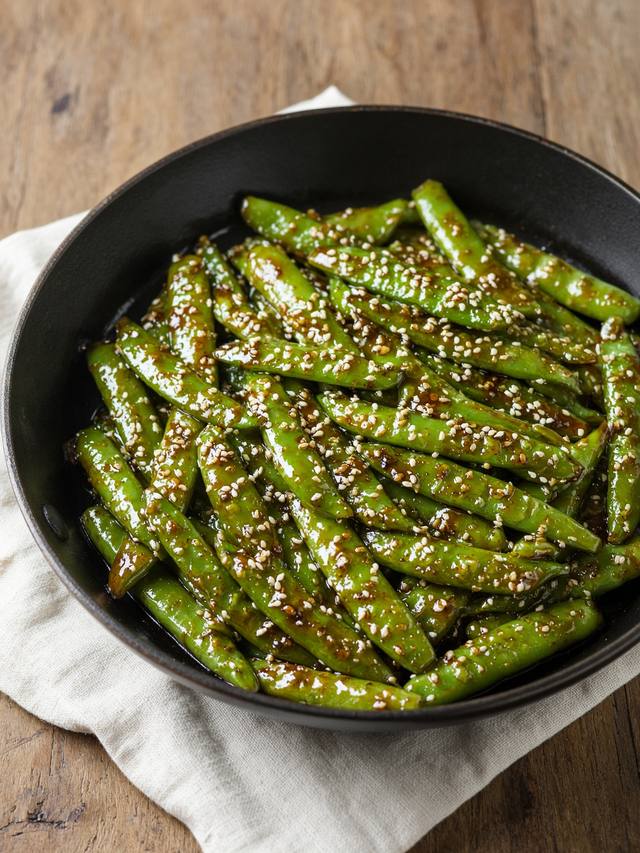Glossy soy-glazed snap peas in a skillet