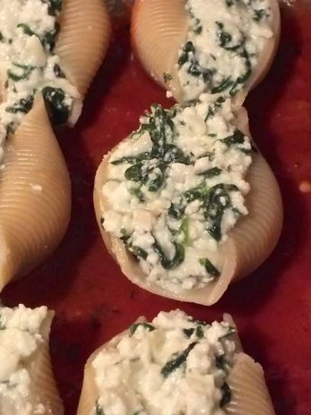 Baked jumbo shells filled with spinach ricotta under red sauce and melted cheese