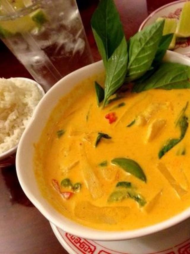 Bowl of creamy coconut chicken soup with mushrooms and lime wedges