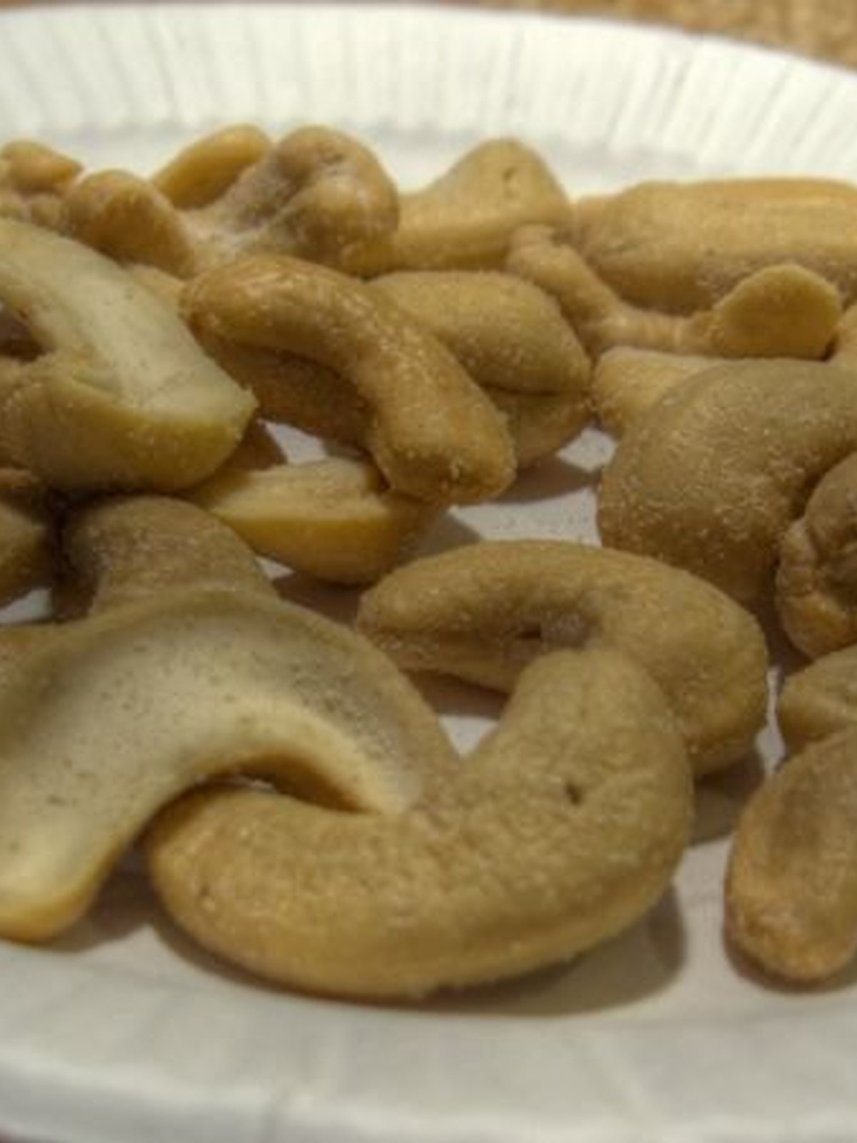 Bowl of glossy honey roasted cashews on a plain surface