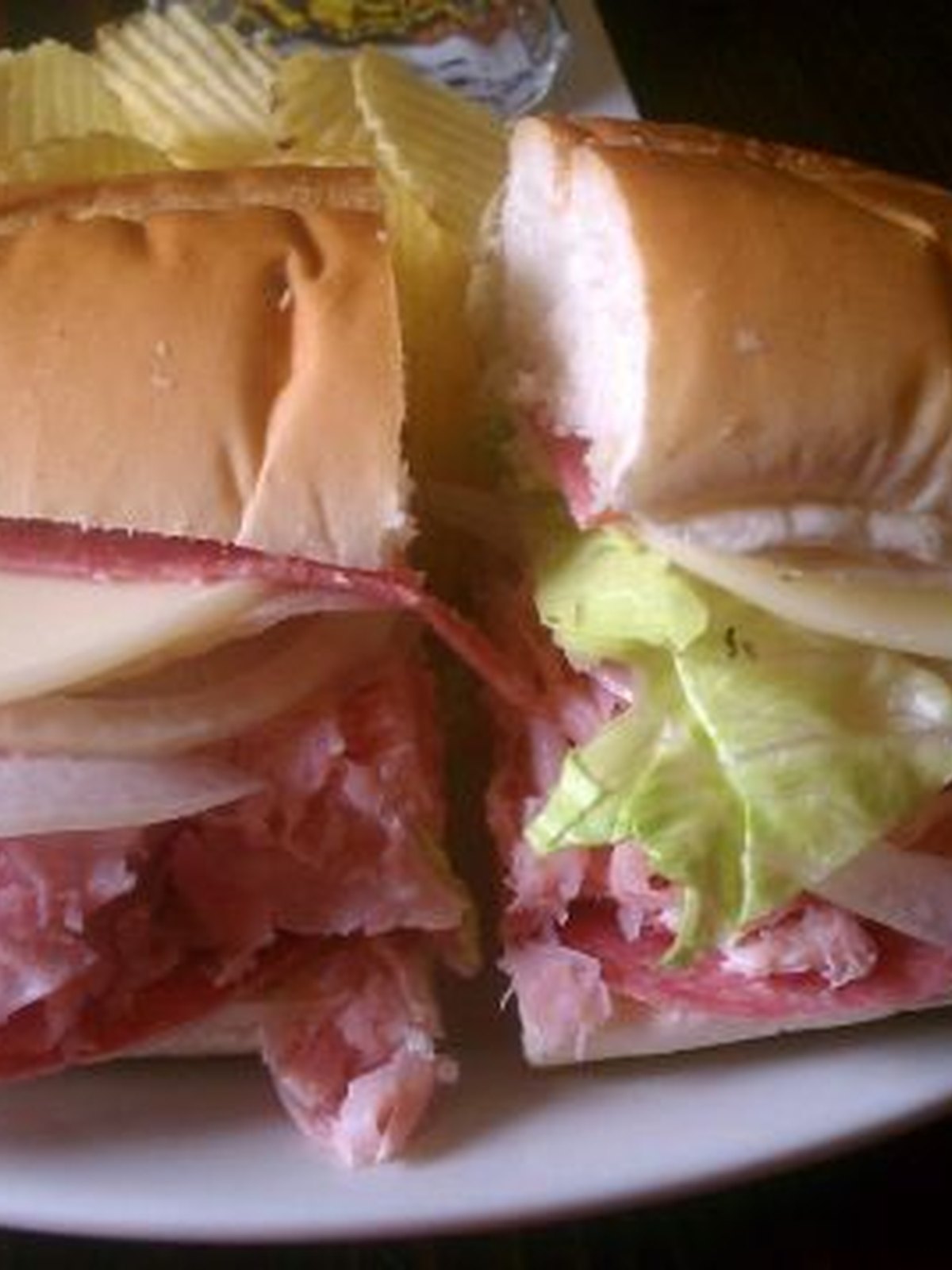 An Italian grinder cut in half, showing meats, cheese, and lettuce