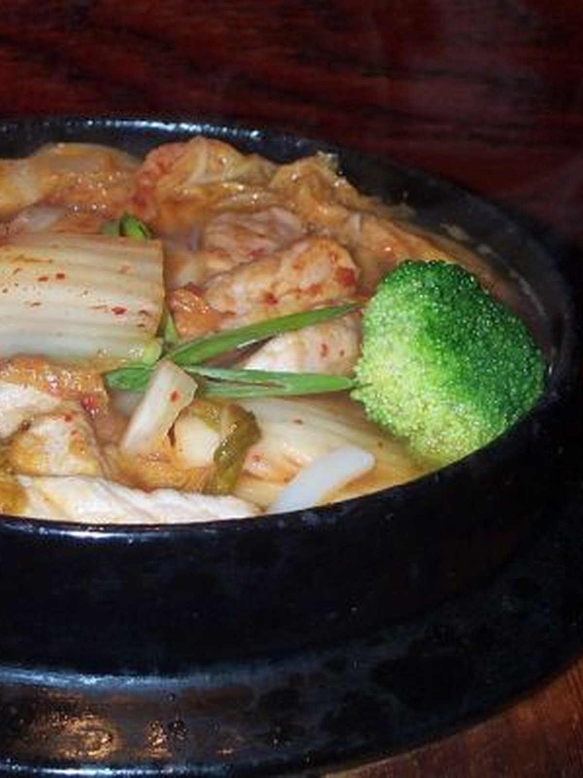 A bowl of kimchi udon with a soft egg and scallions