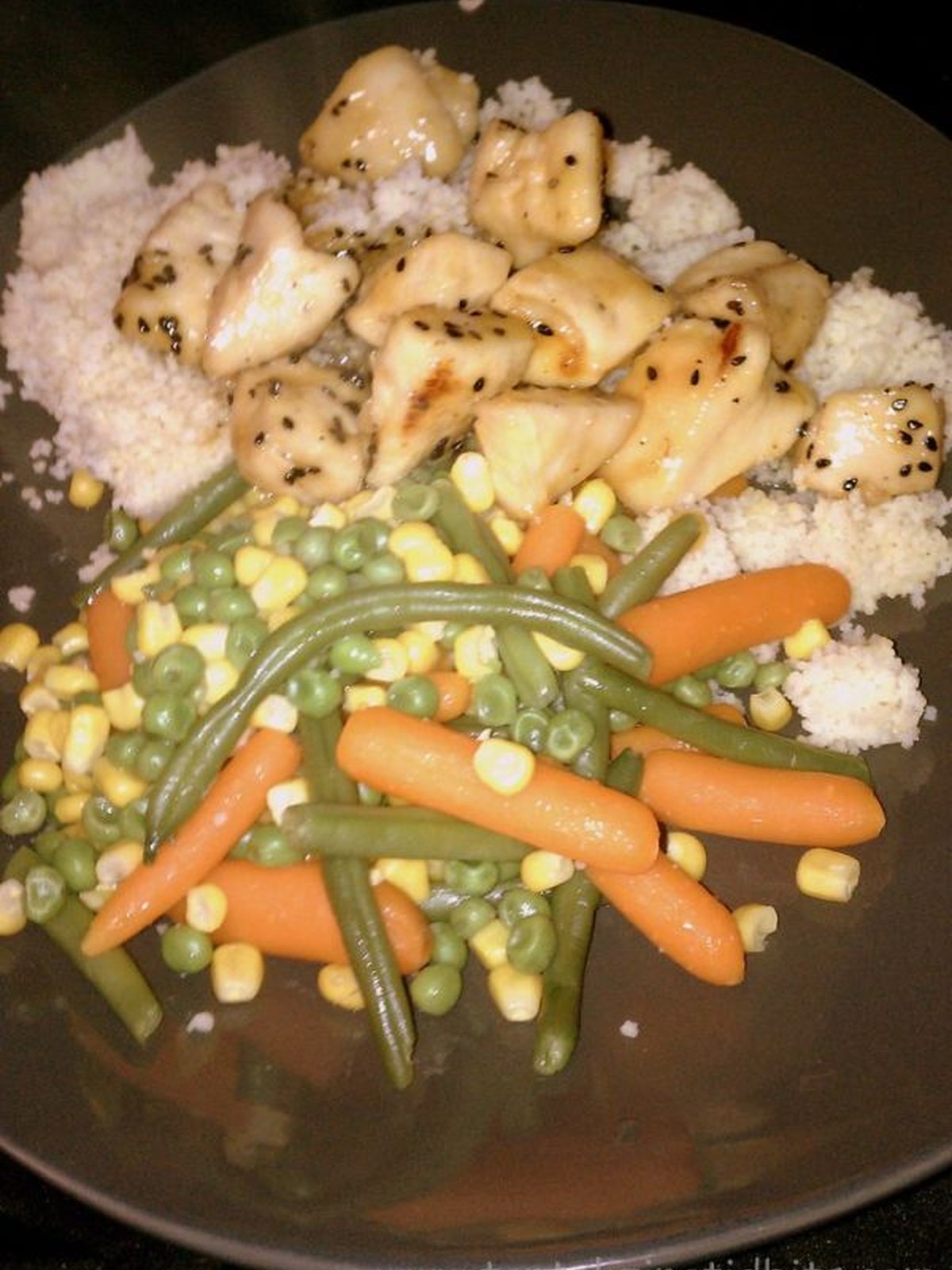 Glazed orange sesame chicken pieces sprinkled with sesame seeds in a skillet