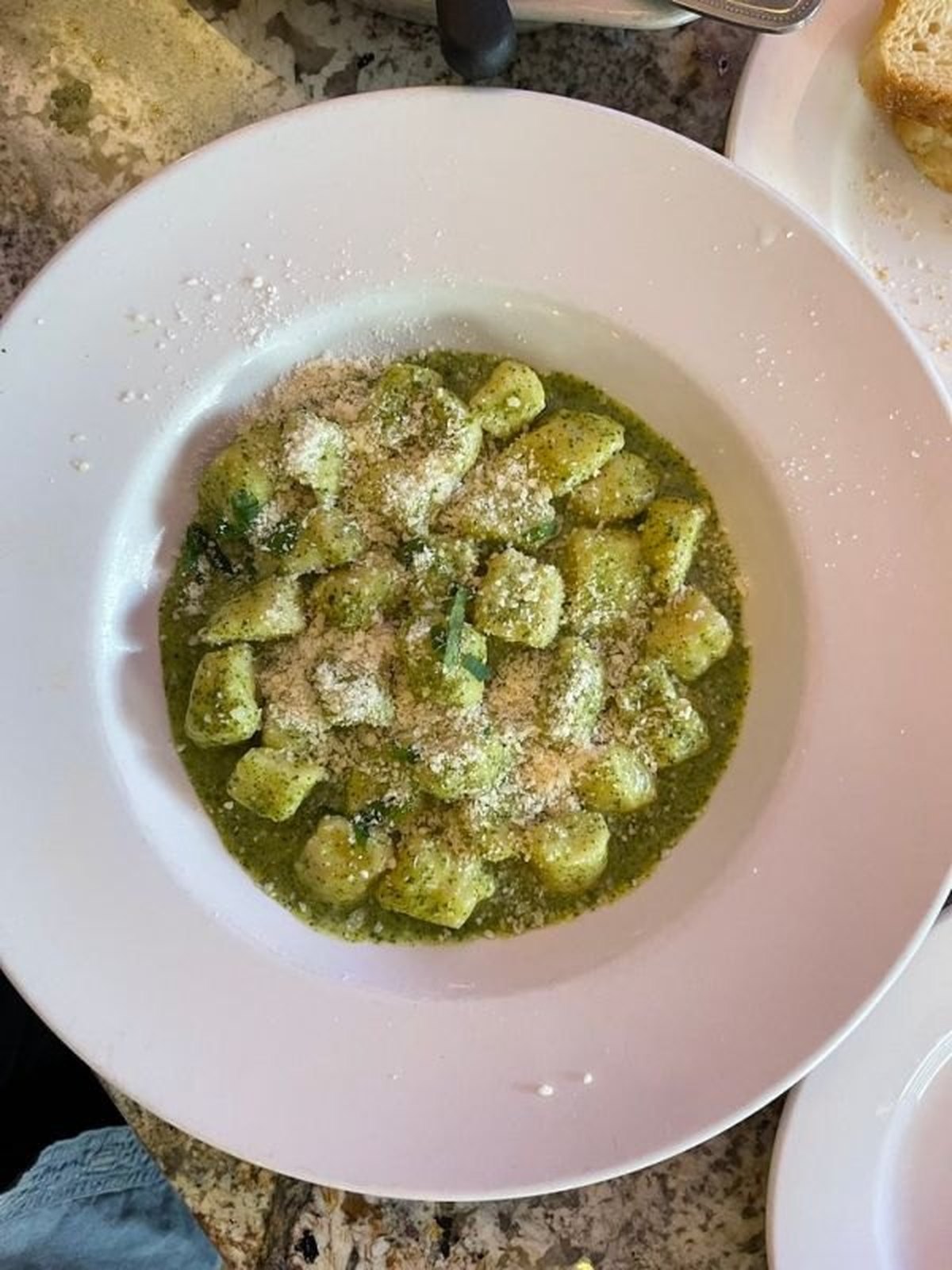 Skillet of seared gnocchi coated in pesto with bright green peas