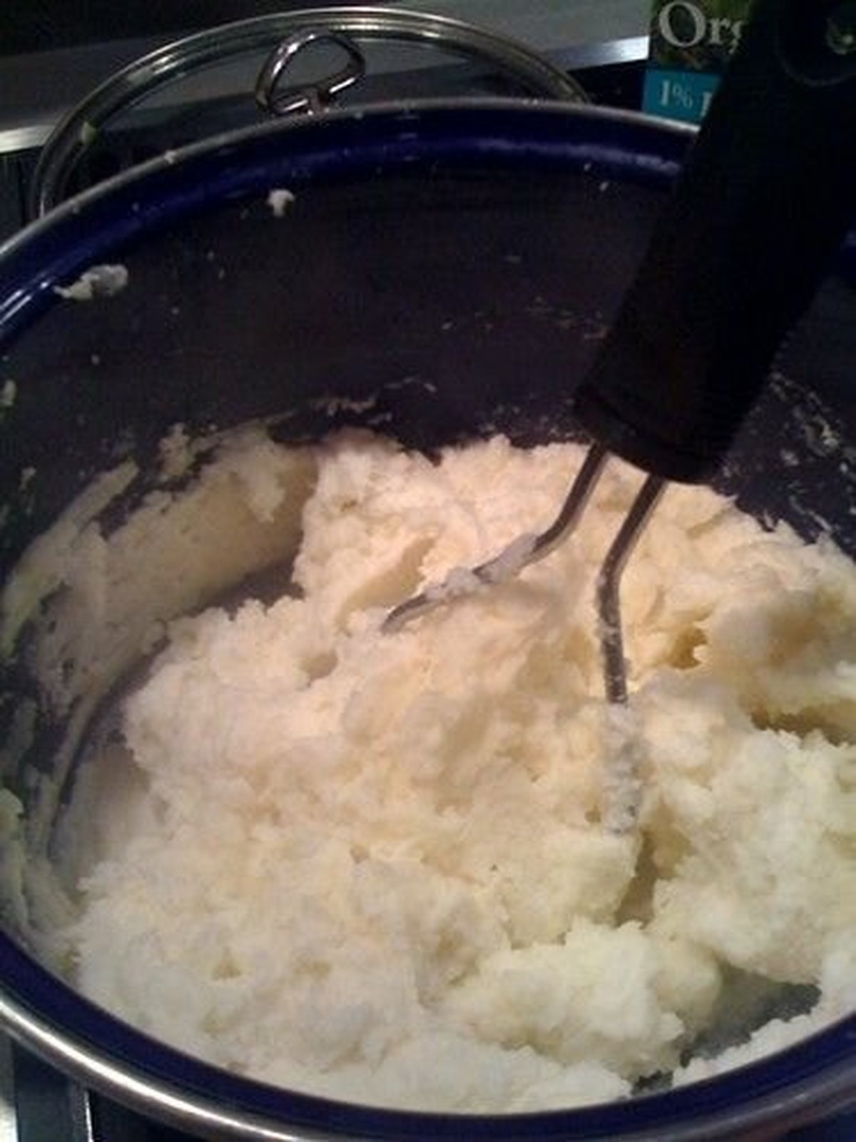 Bowl of fluffy mashed potatoes with chives and a pool of butter